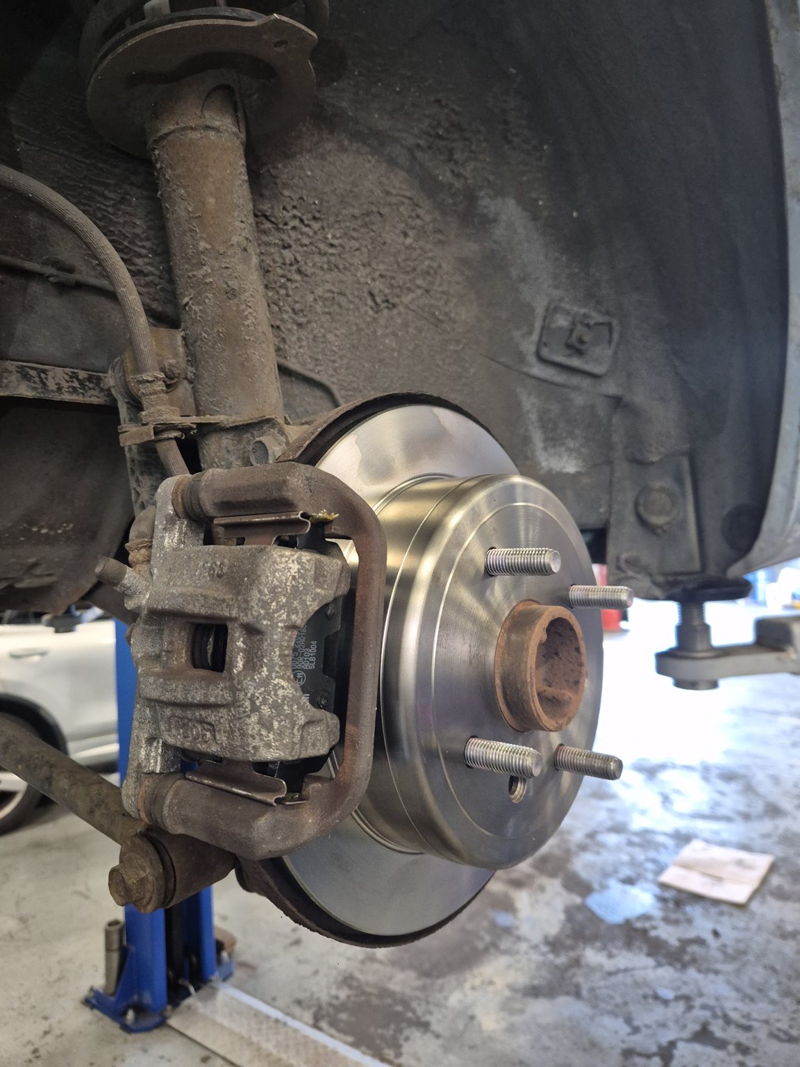 A new brake disc fitted to a rear hub, car up on the lift