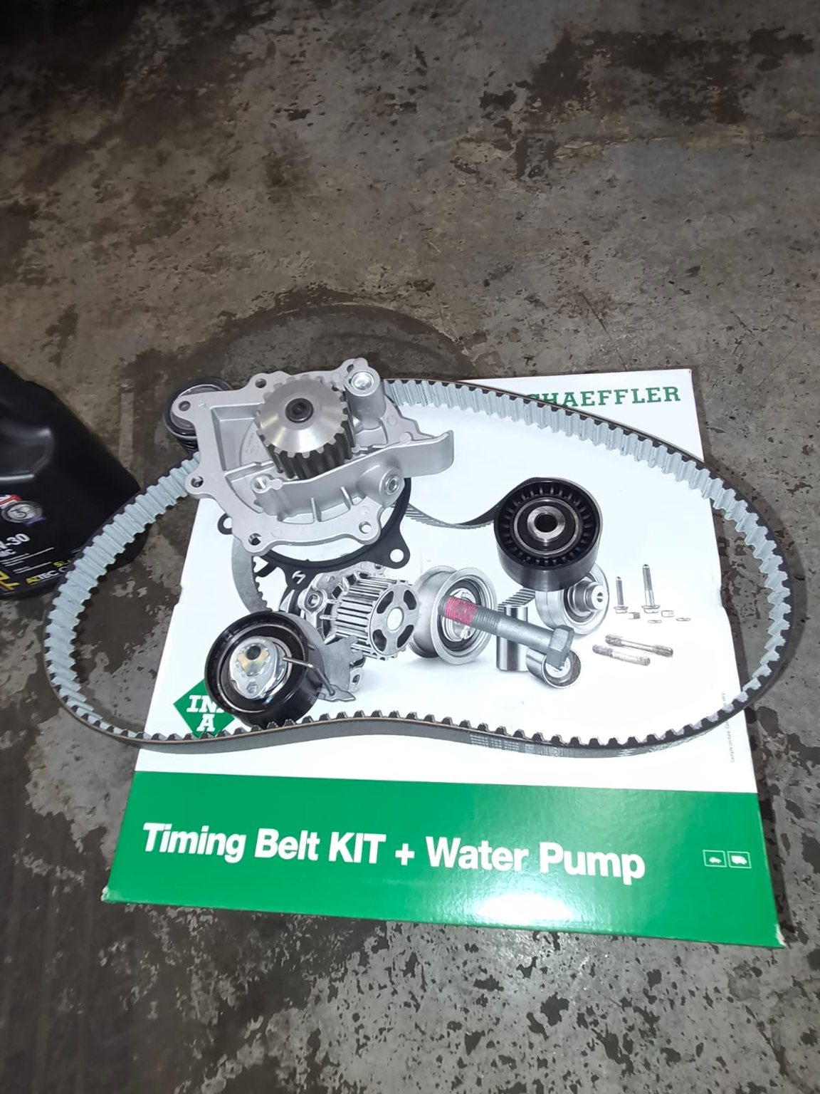 A Schaeffler timing belt kit and water pump laid out on the workshop floor